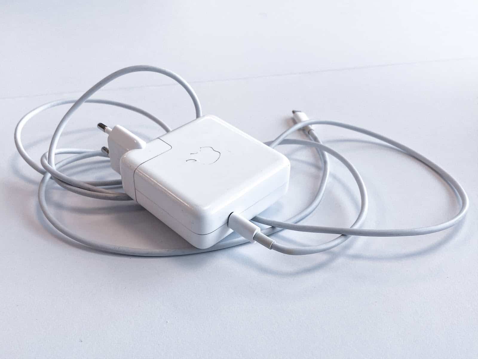 A white Apple laptop charger with cord curled up beneath it.