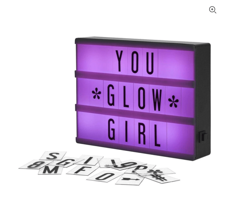 A purple lit cinema box with the word tiles You Glow Girl. Additional letter tiles are scattered in front of the box showing that you can customize it to say anything you want.