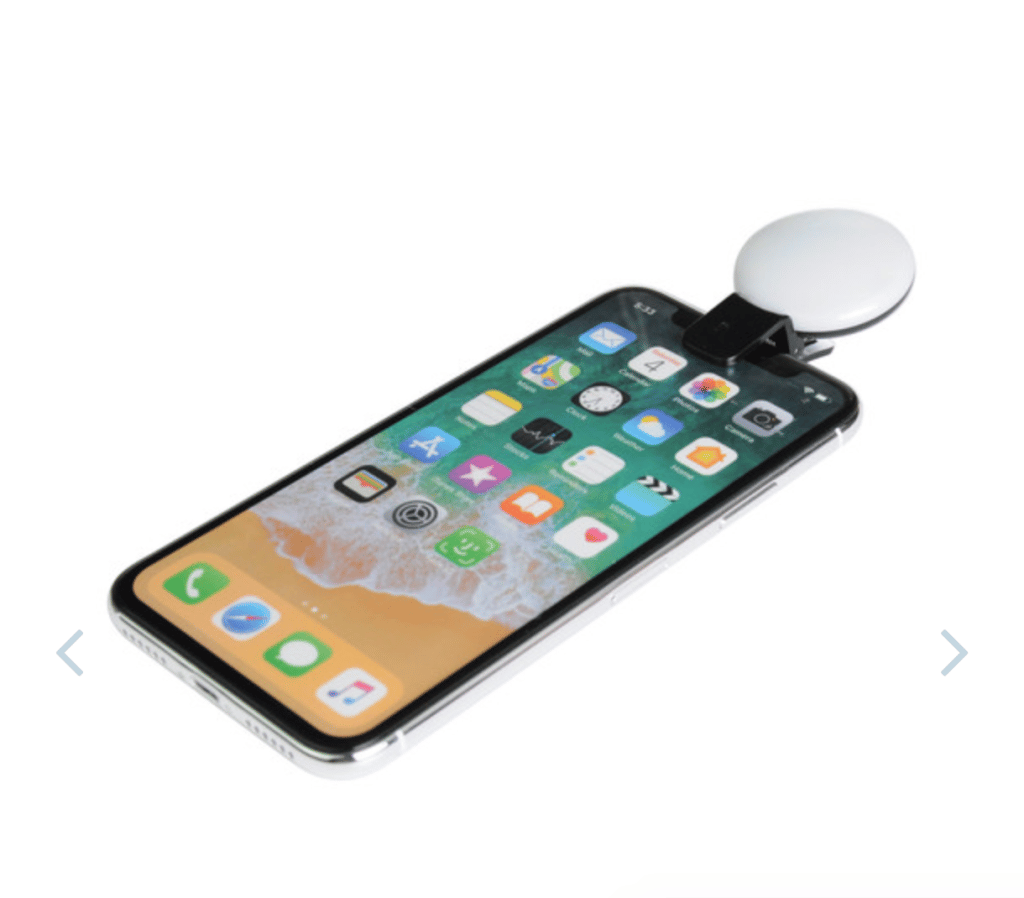 A smart phone with a white circular light attached to the top to enhance lighting and help people appear professional on Zoom calls.