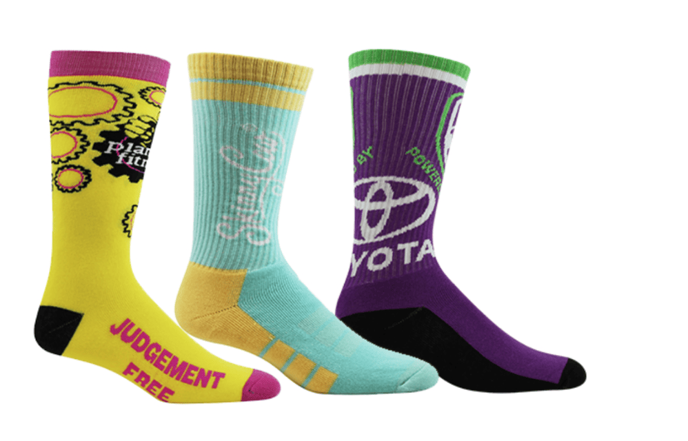 Three brightly colored, customized athletic socks featuring unique designs and bold text, showcasing how branded socks can add personality and school pride to students' outfits.