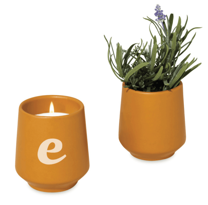 A burning candle and a lavender plant in a planter.