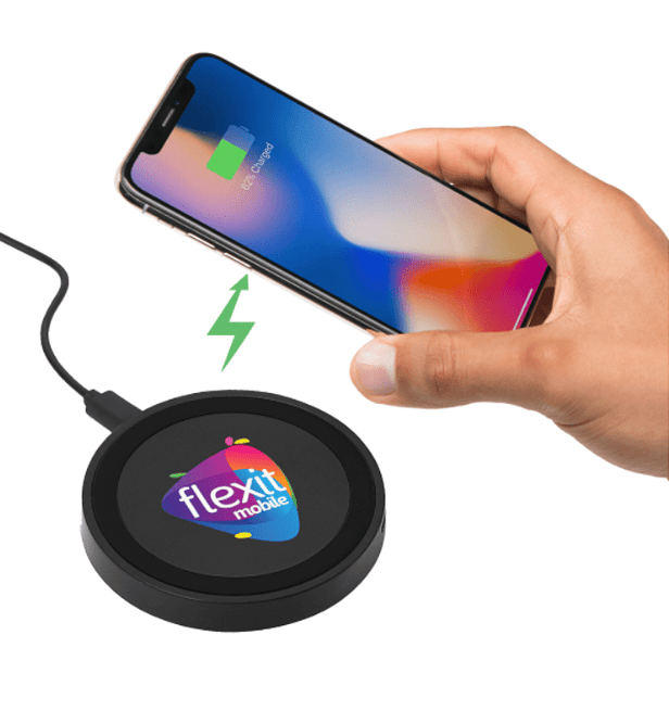 A hand holding a phone over a wireless charging pad.